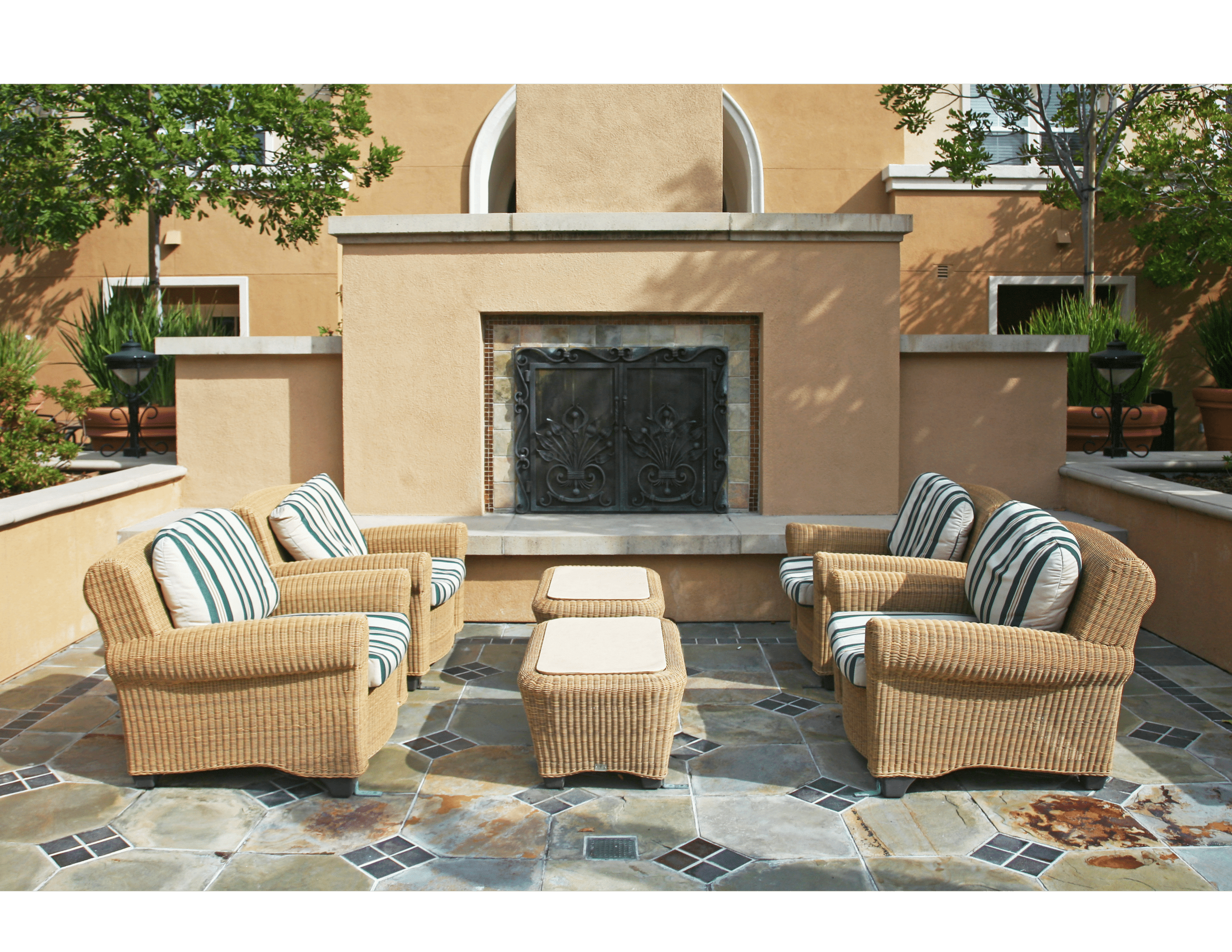 A patio with wicker furniture and a fireplace.