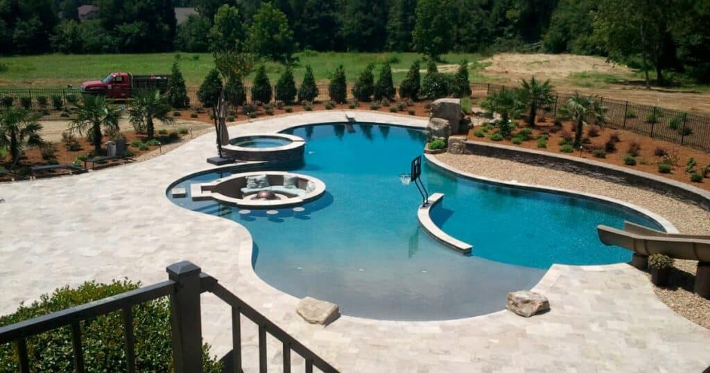 A backyard pool with a slide and waterfall.