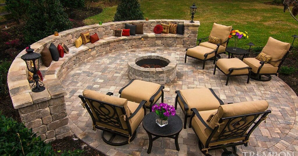 A hardscape design patio with a fire pit and furniture.