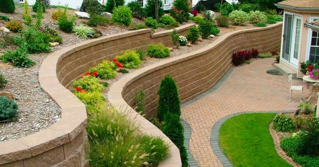 A backyard with a retaining wall and landscaping. 