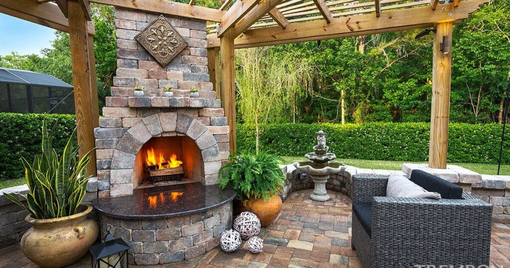 A patio with a stone fireplace and wicker furniture. 