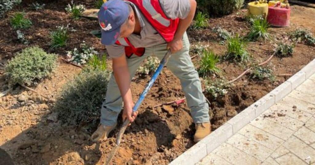 A man with a shovel digging a hole in the ground.