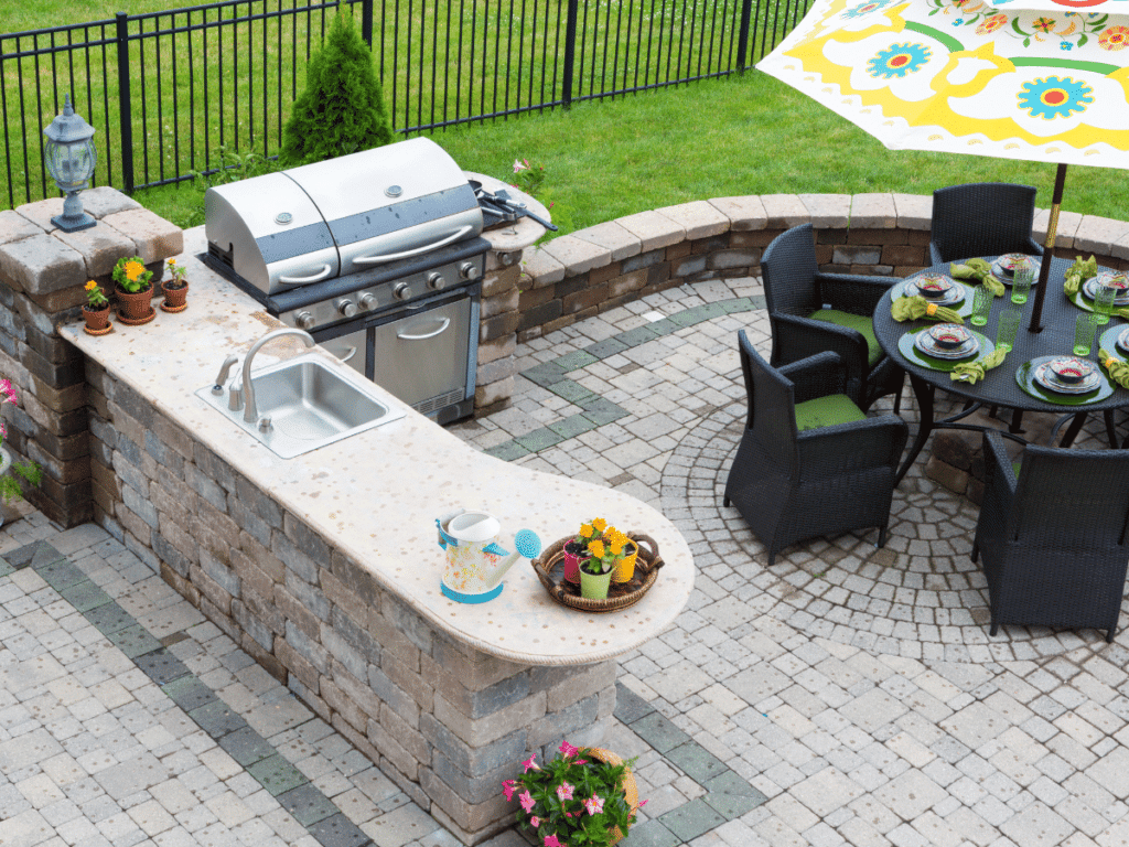 Landscape designer hardscape example: Outdoor patio with a built-in grill, sink, and dining area ready for entertaining.