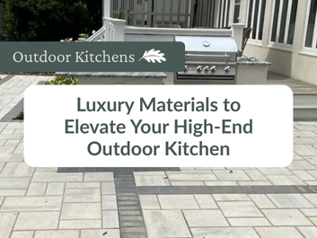 Modern outdoor kitchen with a stainless steel grill, light stone patio, and a banner that reads "Luxury Materials to Elevate Your High-End Outdoor Kitchen.