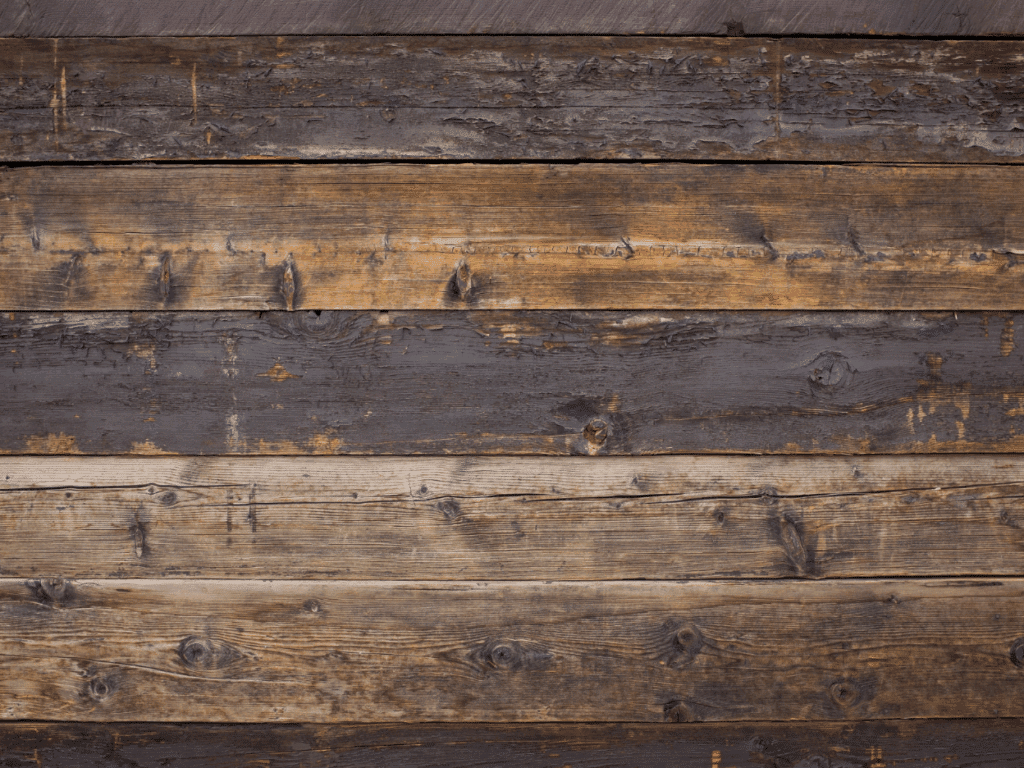 Close-up view of several horizontal wooden planks with visible grain, knots, and weathered textures in shades of brown and gray.