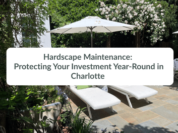 Two white lounge chairs and an umbrella sit on a stone patio surrounded by greenery. Text overlay reads: "Hardscape Maintenance: Protecting Your Investment Year-Round in Charlotte.