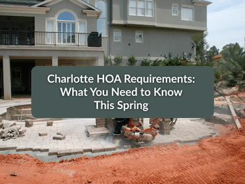 Two workers use a saw to cut pavers in a partially completed front yard; text overlay reads, "Charlotte HOA Requirements: What You Need to Know This Spring.