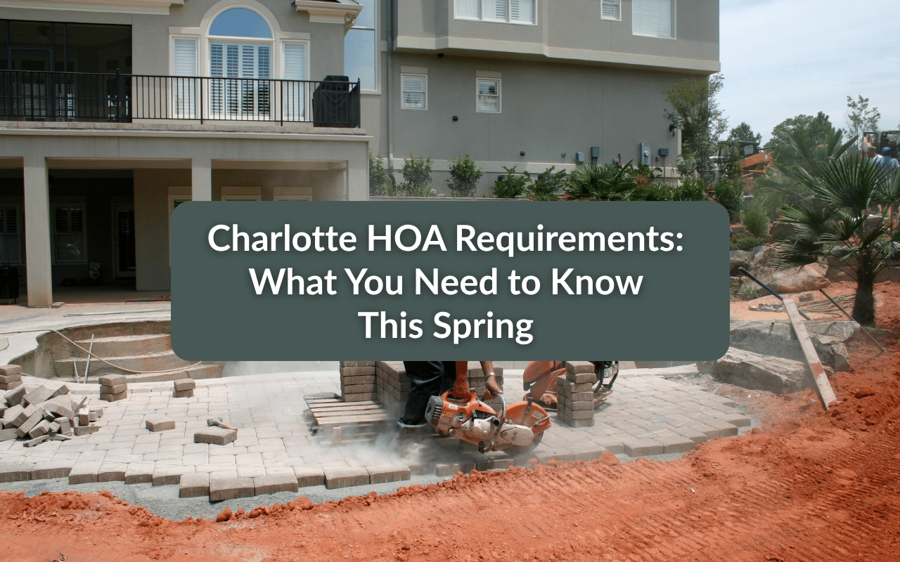Two workers cut paving stones in front of a house under construction; text overlay reads, "Charlotte HOA Requirements: What You Need to Know This Spring.