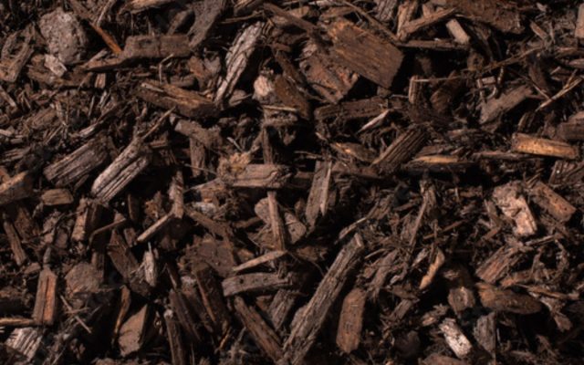 A close-up view of a pile of brown wood mulch pieces, showing rough, uneven texture and various shapes and sizes.