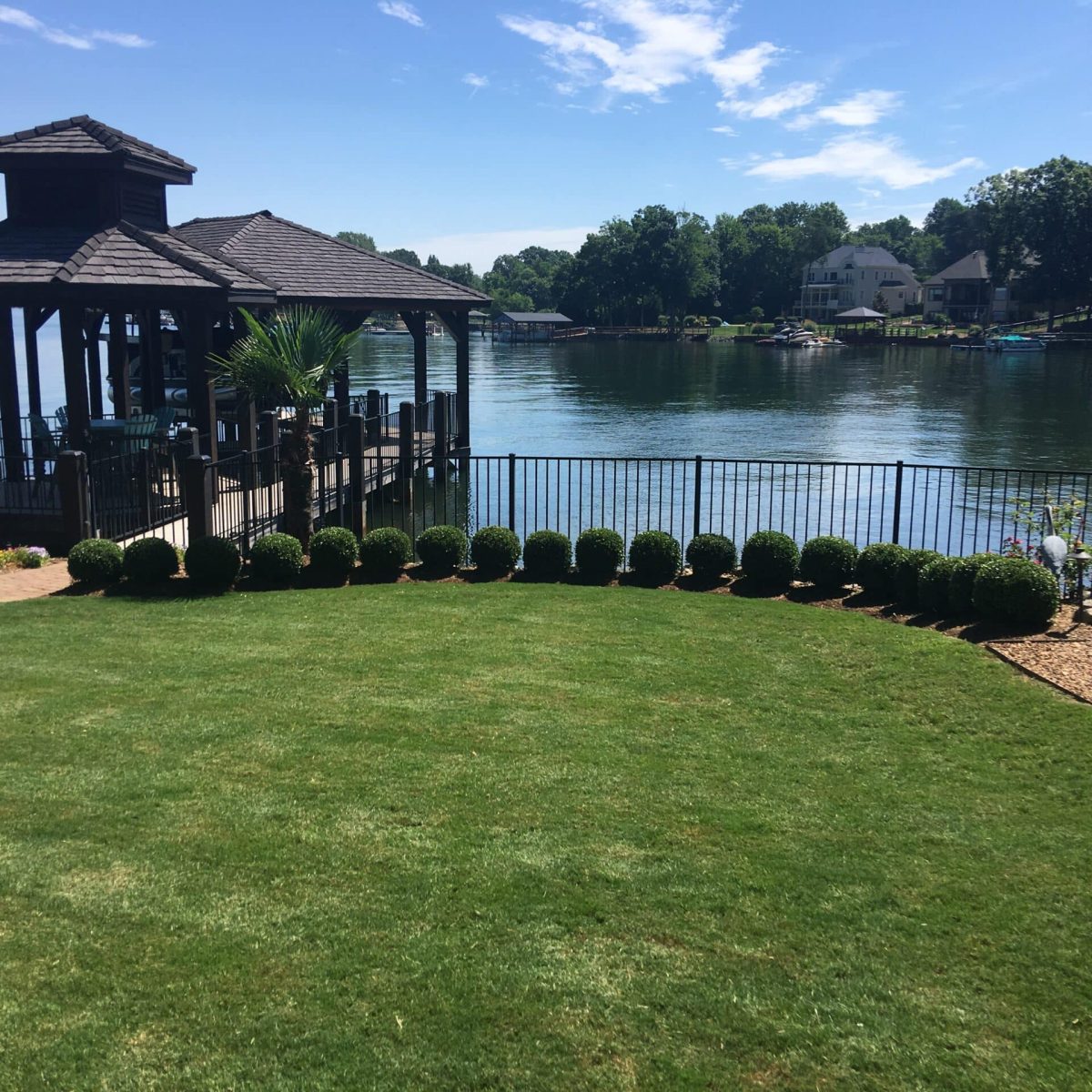 A lawn with a gazebo near a lake.